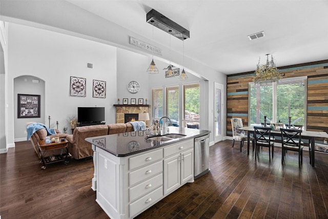 605 Pine Island Cir, Mansfield, TX 76063 - kitchen featuring dishwasher, a tile fireplace, wooden walls, white cabinets, and dark wood finished floors