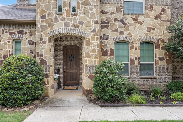605 Pine Island Cir, Mansfield, TX 76063 - view of exterior entry featuring stone siding, roof with shingles, and brick siding