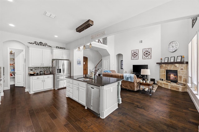 605 Pine Island Cir, Mansfield, TX 76063 - kitchen with appliances with stainless steel finishes, dark countertops, arched walkways, open floor plan, and dark wood finished floors