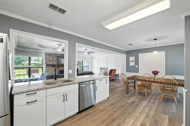 1105 Maree Dr, Waxahachie, TX 75165 - kitchen with stainless steel appliances, light wood-style floors, white cabinets, crown molding, and light stone counters