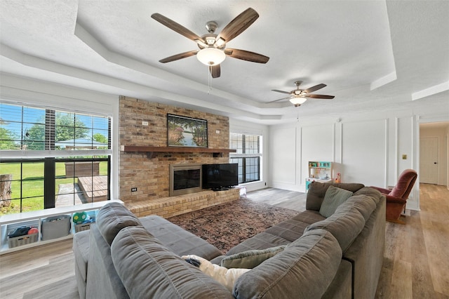 1105 Maree Dr, Waxahachie, TX 75165 - living room featuring a tray ceiling, ceiling fan, healthy amount of natural light, and light wood-style floors