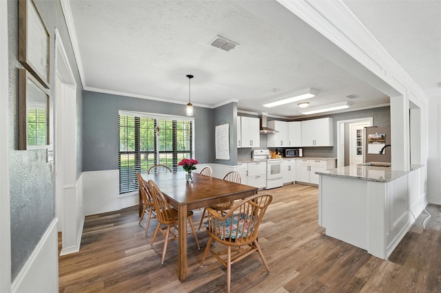 1105 Maree Dr, Waxahachie, TX 75165 - dining area featuring ornamental molding, light wood-style floors, plenty of natural light, and a textured ceiling