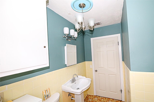 1561 Fm 1816, Bowie, TX 76230 - half bath with tile walls, a chandelier, and a wainscoted wall