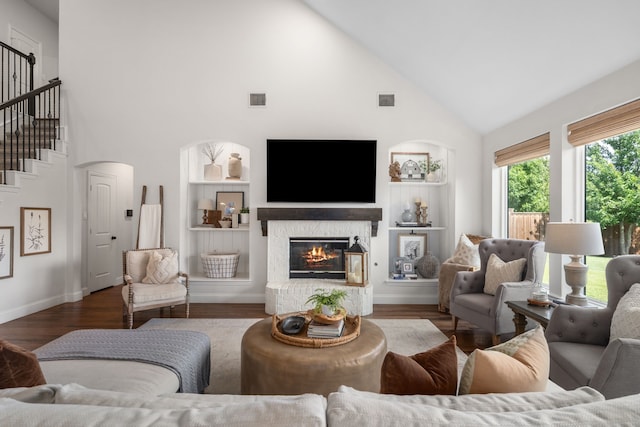750 Camden Way, Prosper, TX 75078 - living area with high vaulted ceiling, a glass covered fireplace, built in features, wood finished floors, and stairs