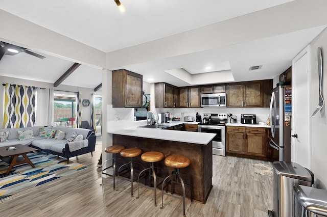 5700 Kingstree Ct, Arlington, TX 76017 - kitchen with stainless steel appliances, open floor plan, light wood-style floors, a kitchen breakfast bar, and a peninsula