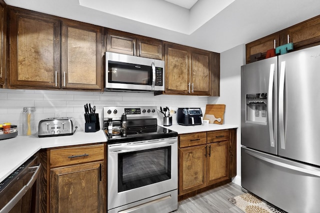 5700 Kingstree Ct, Arlington, TX 76017 - kitchen featuring appliances with stainless steel finishes, light countertops, tasteful backsplash, and light wood-type flooring