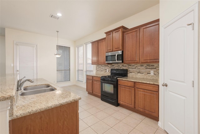 211 Wooded Creek Ave, Wylie, TX 75098 - kitchen with black range with gas cooktop, stainless steel microwave, brown cabinetry, backsplash, and light tile patterned floors