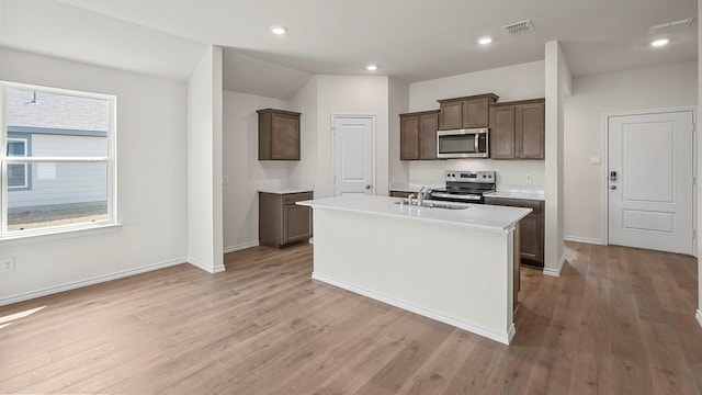 441 Drake Dr, Ferris, TX 75125 - kitchen with stainless steel appliances, a kitchen island with sink, light countertops, light wood-type flooring, and dark brown cabinets