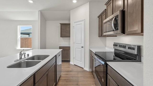 441 Drake Dr, Ferris, TX 75125 - kitchen featuring appliances with stainless steel finishes, wood finished floors, light countertops, dark brown cabinets, and recessed lighting