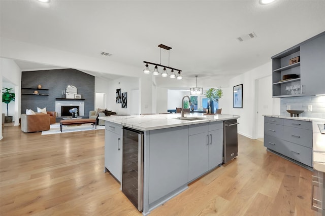 6910 Midcrest Dr, Dallas, TX 75254 - kitchen featuring beverage cooler, gray cabinets, a kitchen island with sink, light wood-style flooring, and vaulted ceiling