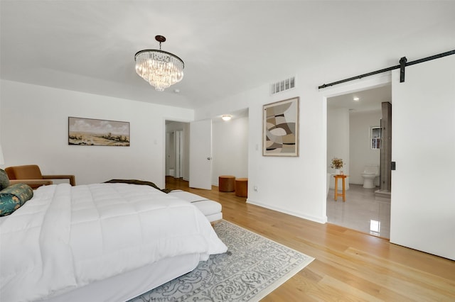 6910 Midcrest Dr, Dallas, TX 75254 - bedroom with a barn door, light wood-type flooring, a chandelier, and ensuite bath