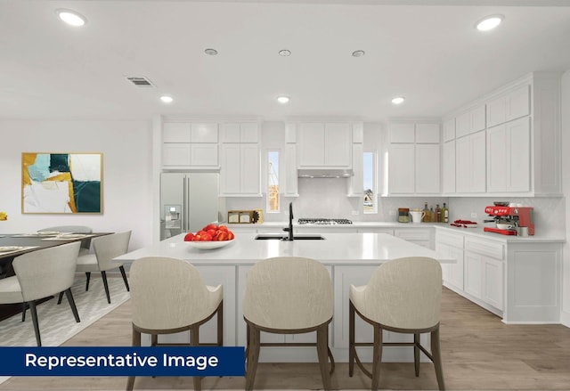 2113 Rockhopper Ct, Mansfield, TX 76063 - kitchen with high quality fridge, tasteful backsplash, an island with sink, a kitchen bar, and light countertops
