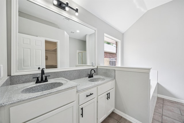 6945 Stockton Dr, Fort Worth, TX 76132 - bathroom with double vanity, lofted ceiling, a walk in closet, tile patterned flooring, and a tub