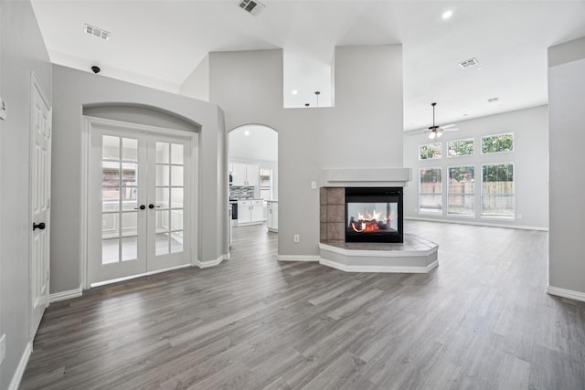 6945 Stockton Dr, Fort Worth, TX 76132 - unfurnished living room featuring a ceiling fan, wood finished floors, a multi sided fireplace, french doors, and arched walkways
