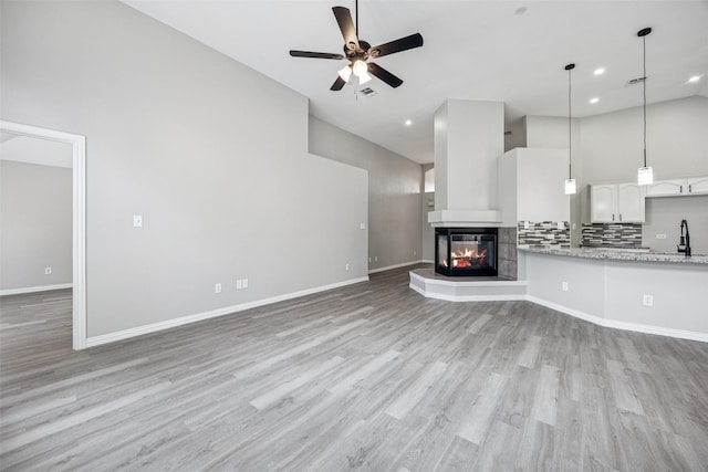6945 Stockton Dr, Fort Worth, TX 76132 - unfurnished living room featuring a ceiling fan, light wood-type flooring, a multi sided fireplace, high vaulted ceiling, and recessed lighting