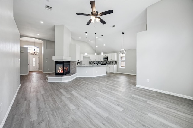 6945 Stockton Dr, Fort Worth, TX 76132 - unfurnished living room featuring ceiling fan, a multi sided fireplace, light wood-style flooring, recessed lighting, and high vaulted ceiling