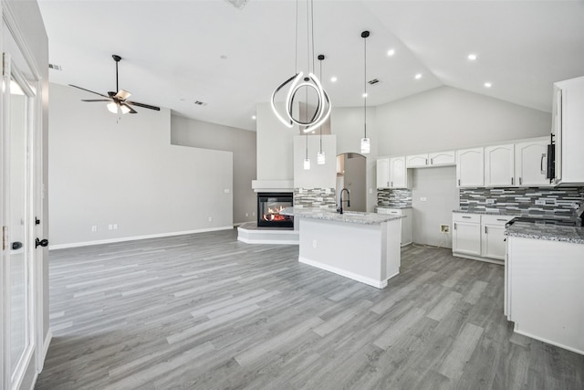 6945 Stockton Dr, Fort Worth, TX 76132 - kitchen featuring open floor plan, ceiling fan, high vaulted ceiling, decorative backsplash, and a multi sided fireplace
