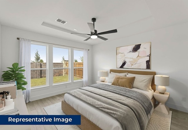 1403 Heron St, Mansfield, TX 76063 - bedroom with light wood-style flooring, a raised ceiling, and ceiling fan