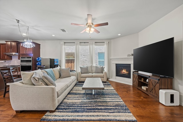 2025 Meliana Dr, Little Elm, TX 75068 - living room featuring a glass covered fireplace, ceiling fan, a chandelier, dark wood-style floors, and recessed lighting
