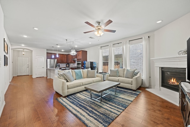 2025 Meliana Dr, Little Elm, TX 75068 - living area featuring recessed lighting, a ceiling fan, wood finished floors, a glass covered fireplace, and arched walkways