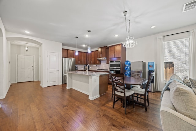 2025 Meliana Dr, Little Elm, TX 75068 - kitchen featuring appliances with stainless steel finishes, arched walkways, open floor plan, dark wood-style floors, and recessed lighting