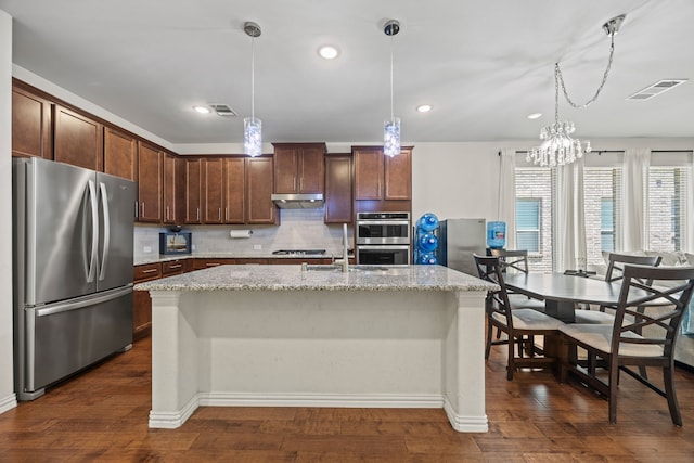 2025 Meliana Dr, Little Elm, TX 75068 - kitchen with appliances with stainless steel finishes, under cabinet range hood, backsplash, light stone counters, and recessed lighting