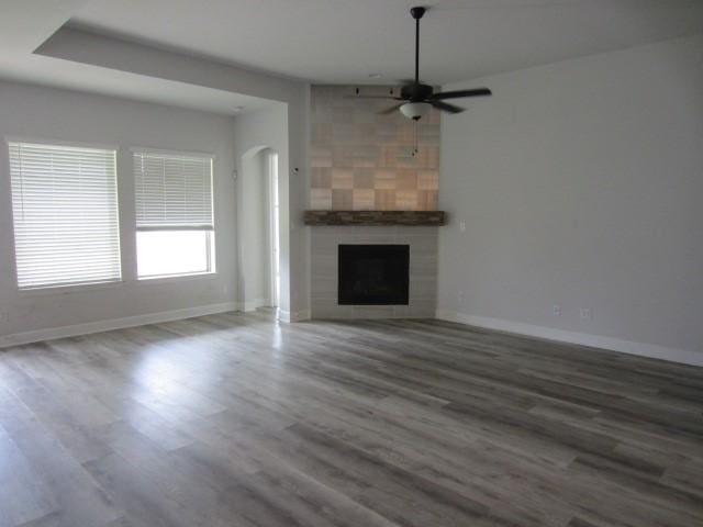 1813 Terrace Way, Argyle, TX 76226 - unfurnished living room with ceiling fan, wood finished floors, a fireplace, and arched walkways