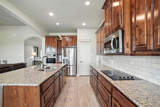 12022 Livingston Way, Talty, TX 75126 - kitchen with stainless steel appliances, arched walkways, light stone counters, decorative backsplash, and light wood finished floors