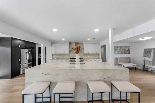 12211 Quincy Ln, Dallas, TX 75230 - kitchen with freestanding refrigerator, a kitchen bar, light stone countertops, recessed lighting, and white cabinets