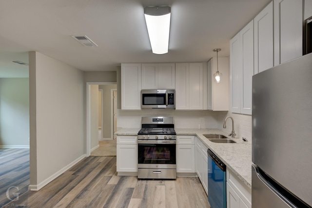 6312 Canal Blvd, Shreveport, LA 71108 - kitchen with appliances with stainless steel finishes, light wood-style floors, white cabinets, light stone countertops, and decorative light fixtures