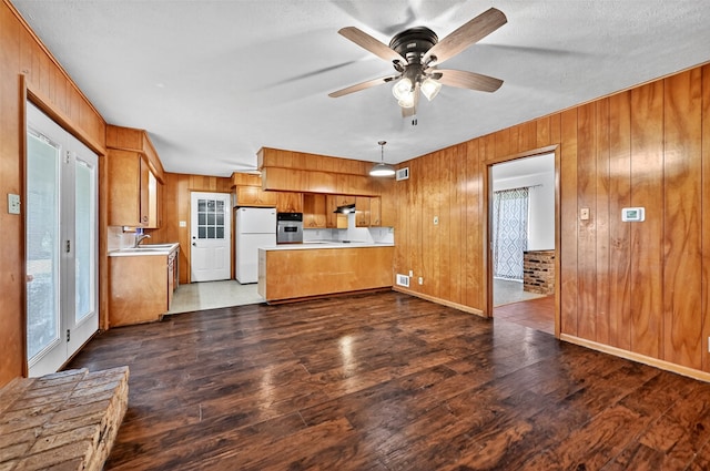 12906 Fm 902, Dorchester, TX 75459 - kitchen with freestanding refrigerator, oven, brown cabinets, light countertops, and wooden walls