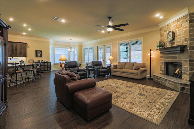 6923 Saint Anthony Dr, Tyler, TX 75703 - living area featuring a stone fireplace, crown molding, ceiling fan, a chandelier, and dark wood-type flooring