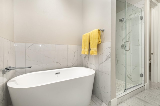 770 N Plano Rd Unit 202, Richardson, TX 75081 - bathroom with tile walls, a marble finish shower, a freestanding bath, marble finish floors, and wainscoting