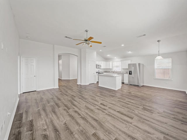 8705 Autumn Creek Trl, Fort Worth, TX 76134 - unfurnished living room with arched walkways, a ceiling fan, lofted ceiling, wood finished floors, and plenty of natural light