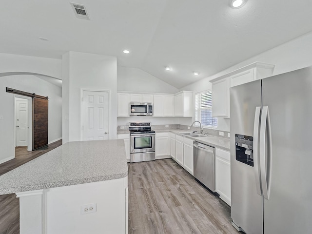 8705 Autumn Creek Trl, Fort Worth, TX 76134 - kitchen with appliances with stainless steel finishes, a barn door, lofted ceiling, light wood-style flooring, and light countertops
