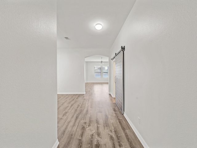 8705 Autumn Creek Trl, Fort Worth, TX 76134 - corridor featuring light wood-style flooring, a barn door, and arched walkways