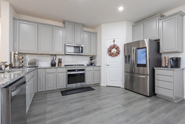18137 Lakefront Ct, Forney, TX 75126 - kitchen with stainless steel appliances, gray cabinetry, light wood-style floors, and tasteful backsplash