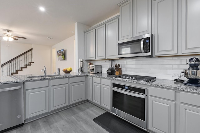 18137 Lakefront Ct, Forney, TX 75126 - kitchen with stainless steel appliances, gray cabinets, light wood-type flooring, a ceiling fan, and tasteful backsplash