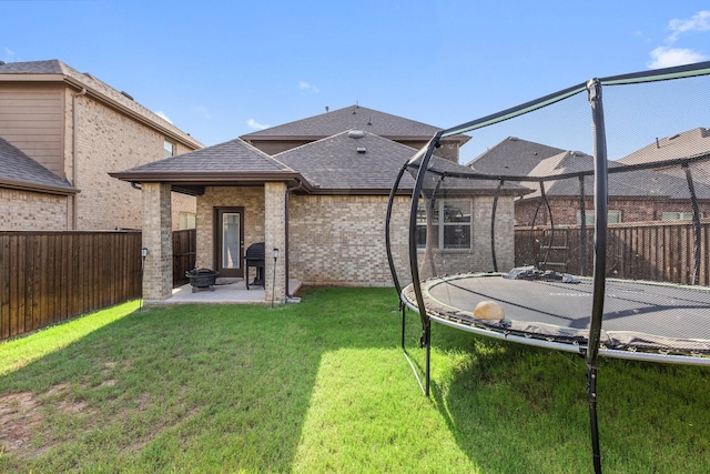 18137 Lakefront Ct, Forney, TX 75126 - back of house with a patio, a trampoline, a fenced backyard, a shingled roof, and brick siding