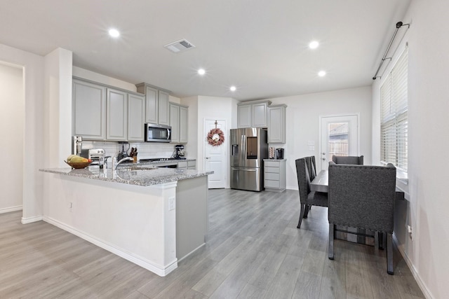 18137 Lakefront Ct, Forney, TX 75126 - kitchen featuring stainless steel appliances, gray cabinetry, light stone countertops, a peninsula, and recessed lighting