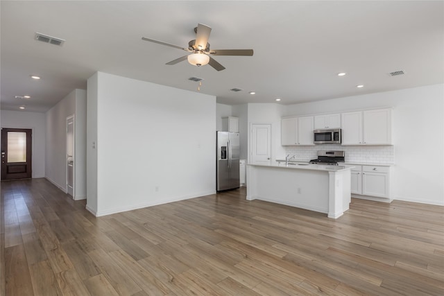 204 Post Oak St, Azle, TX 76020 - kitchen featuring stainless steel appliances, open floor plan, a ceiling fan, light wood-style floors, and white cabinetry