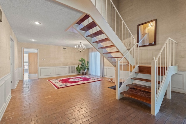 1605 Lamberth Cir, Sherman, TX 75092 - stairway with a textured ceiling, a decorative wall, brick floors, wainscoting, and a chandelier