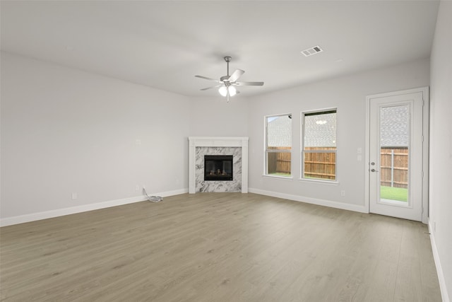 2297 High Plain Ln, Waxahachie, TX 75167 - unfurnished living room featuring plenty of natural light, a ceiling fan, a high end fireplace, and light wood-type flooring