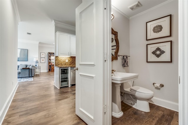 3303 Blackburn St Unit 308, Dallas, TX 75204 - half bathroom featuring wine cooler, crown molding, wood finished floors, and decorative backsplash