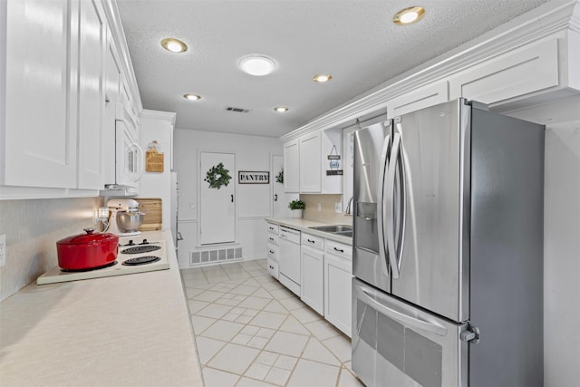 6737 Oliver Dr, North Richland Hills, TX 76180 - kitchen with white appliances, light countertops, white cabinets, a textured ceiling, and light tile patterned floors