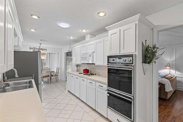 6737 Oliver Dr, North Richland Hills, TX 76180 - kitchen with white appliances, white cabinetry, light countertops, a textured ceiling, and recessed lighting