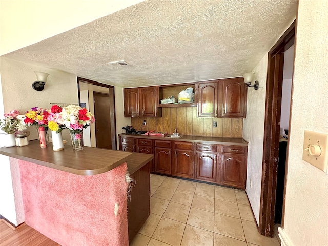 1125 Siebold Ct, Mesquite, TX 75150 - kitchen featuring a textured wall, a peninsula, a textured ceiling, dark countertops, and open shelves