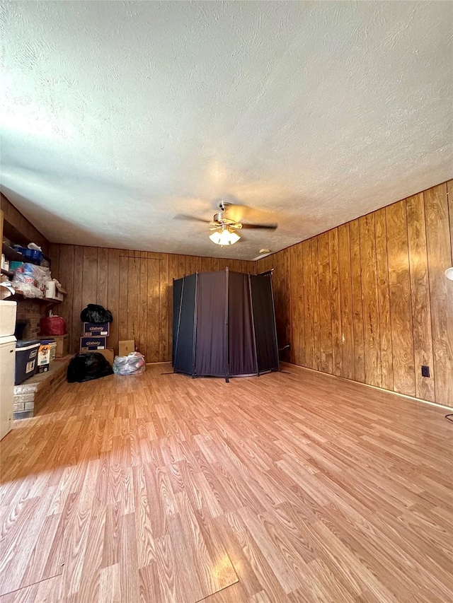 1125 Siebold Ct, Mesquite, TX 75150 - spare room featuring light wood-style flooring, a textured ceiling, a ceiling fan, and wood walls