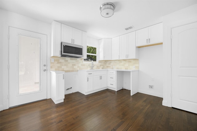2267 Tealford Dr, Dallas, TX 75228 - kitchen with stainless steel microwave, backsplash, dark wood-style flooring, and white cabinetry