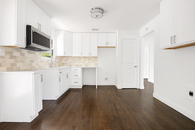 2267 Tealford Dr, Dallas, TX 75228 - kitchen featuring stainless steel microwave, decorative backsplash, dark wood-style flooring, white cabinetry, and light countertops